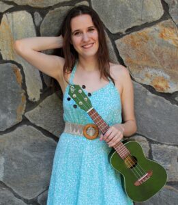 Ukulele instructor/performer Abby Lyons holding a green ukulele.