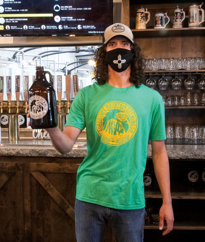 Employee at Guadalupe mountain brewery holding up a growler 