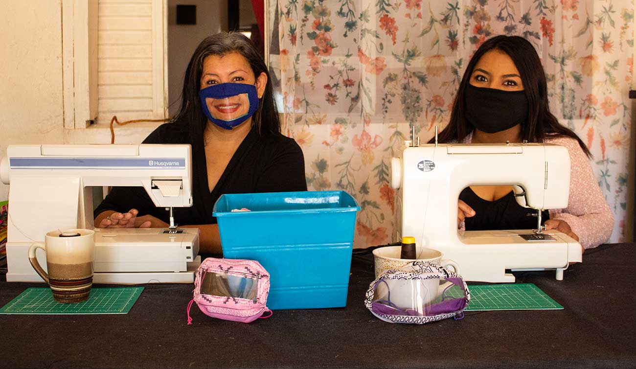 Two women at sewing machines making masks