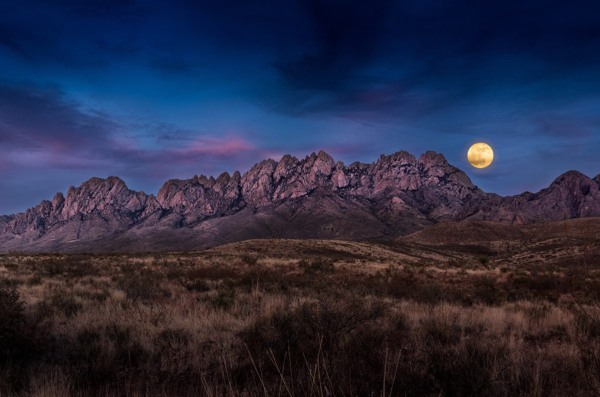 Organ Mountains with full moon rising behind them.