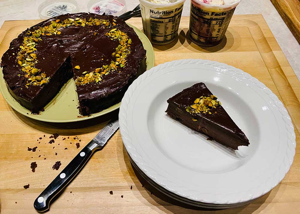slice of chocolate cake on a plate next to the whole cake.