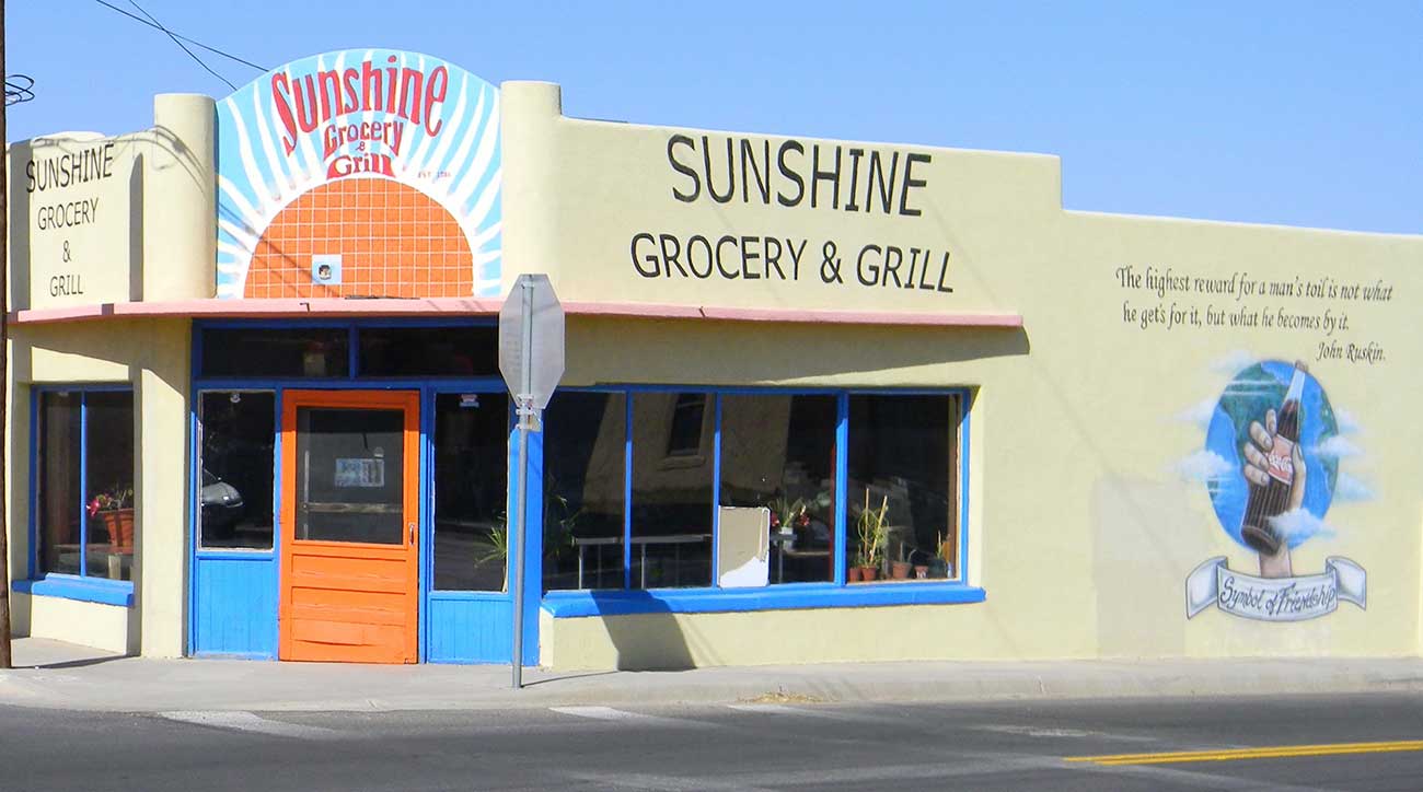 Building with bright mural and Sunshine Grocery & Grill on side