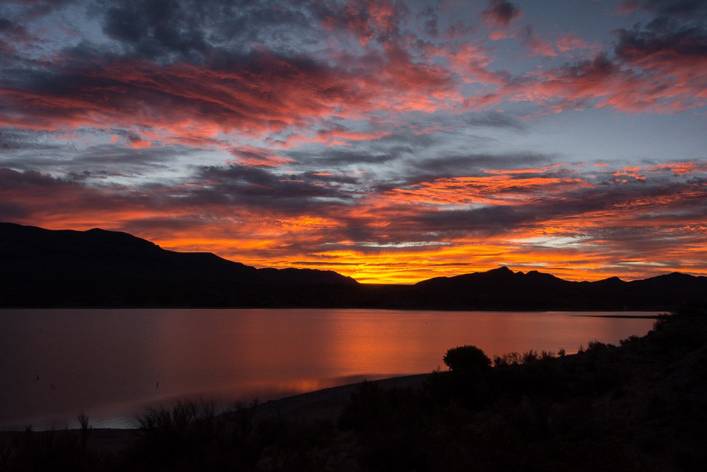 Caballo Lake State Park during sunset with the orange reys reflecting off the water.