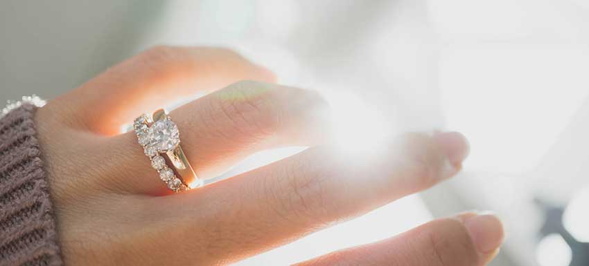 Hand with a diamond engagement ring set.